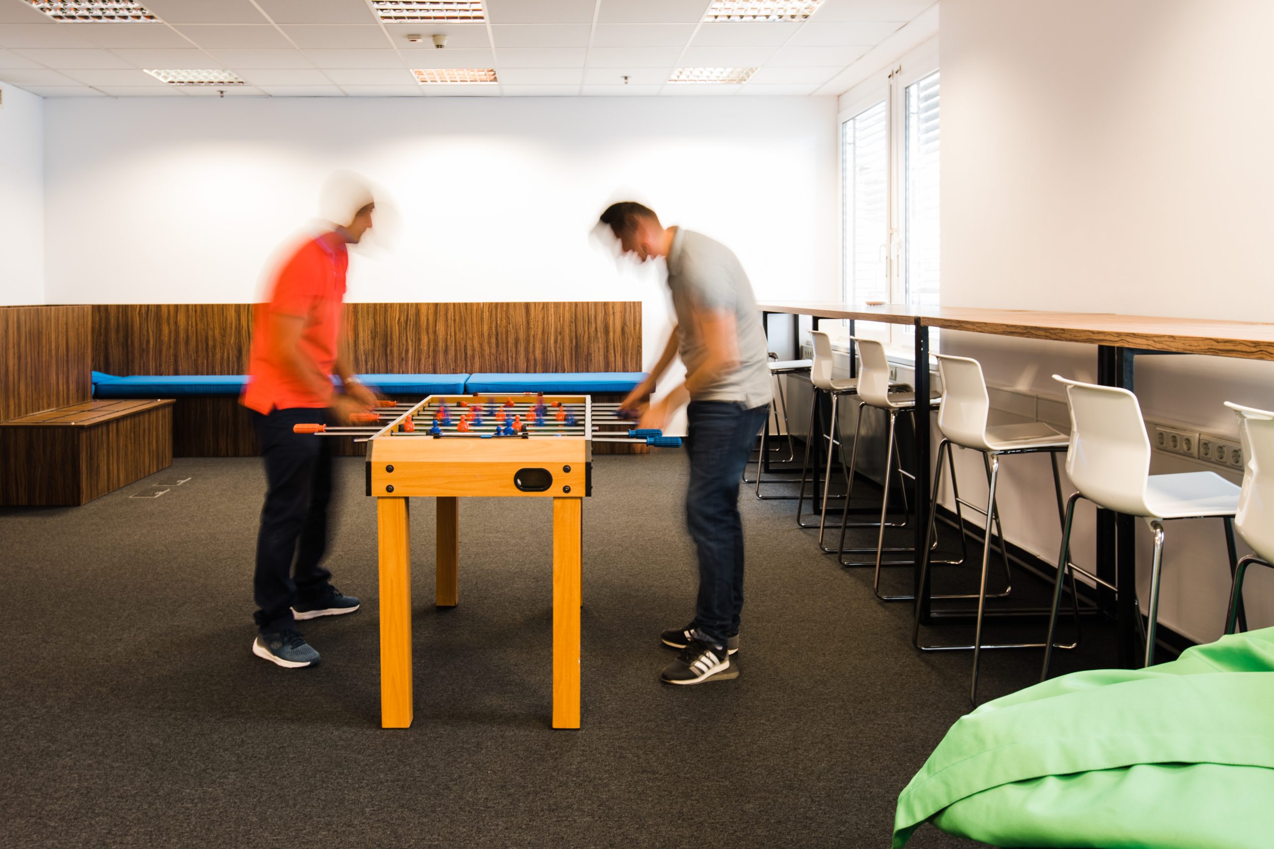 Networking în spațiu de coworking, doi membri jucând fotbal de masă într-o zonă comună